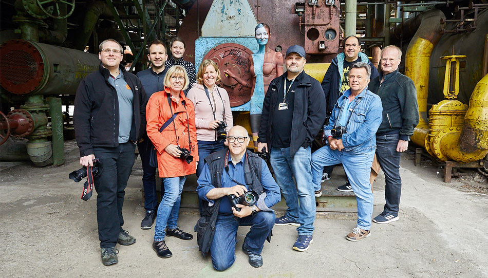 Fujifilm X Photographer Reinhard Loher (4. v. r.) lässt mit den Teilnehmern seines Workshops „Bodypainting in der Industriekulisse“ ein Model im Landschaftspark fast verschwinden.